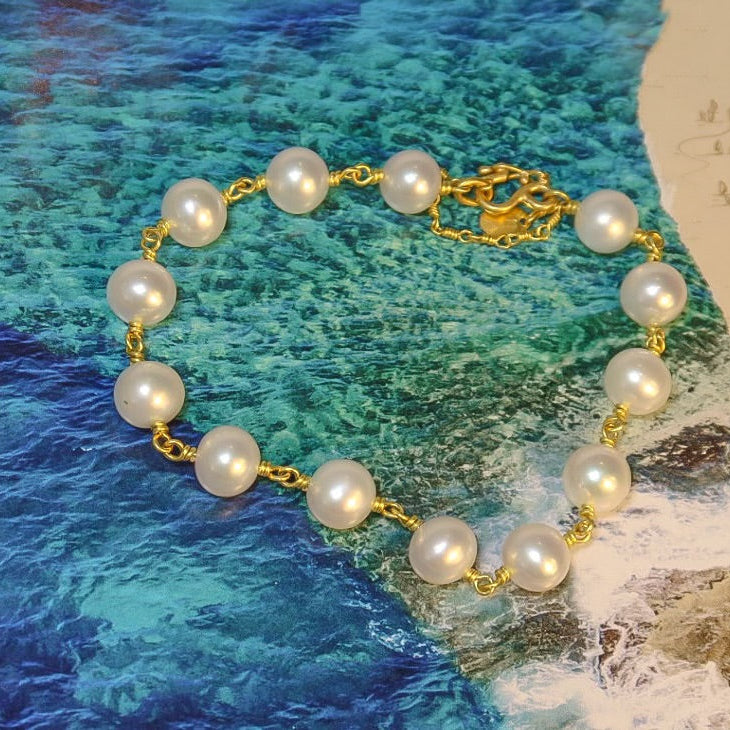Pearl bracelet with gold chain on a textured blue and green background